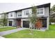 Modern townhome featuring a two-story design, a dark two-car garage, and gray and white color scheme at 4417 Le Reve Ct, Kissimmee, FL 34746