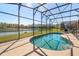 Sparkling screened-in backyard pool offering a tranquil view of the lake and greenery at 4692 Sw Golden Beach N Ct, Kissimmee, FL 34746