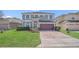 Charming two-story home featuring a well-manicured lawn, brick driveway and a attached two-car garage at 545 Fairhaven Dr, Davenport, FL 33837