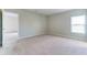 This spacious bedroom features neutral colored walls and carpet and a large window at 64 Citrine Loop, Kissimmee, FL 34758