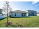 Back exterior view of the house featuring a cozy patio and green lawn at 64 Citrine Loop, Kissimmee, FL 34758