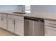 Close-up of a kitchen island with a sink, stainless steel dishwasher, and sleek white cabinets at 64 Citrine Loop, Kissimmee, FL 34758