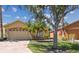 Exterior view of home with two car garage and manicured lawn with mature shade trees at 782 Vineyard Way, Poinciana, FL 34759