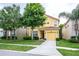 Charming two-story home features a yellow facade, attached garage, and well-maintained landscaping at 8945 Cuban Palm Rd, Kissimmee, FL 34747