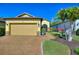 Charming single-story home featuring a brick driveway, a two-car garage, and lush landscaping at 104 La Cresta Ct, Davenport, FL 33837