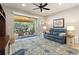 Cozy living room with blue sofa, ceiling fan, and sliding glass doors to screened patio with wicker furniture at 104 La Cresta Ct, Davenport, FL 33837