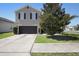 A two-story gray home with a black garage door and a well-maintained lawn with a tree at 1246 Maplebrook Dr, Lake Alfred, FL 33850