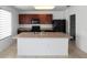 Kitchen island with a dual stainless steel basin sink, white cabinets, tile floors, and black appliances at 1246 Maplebrook Dr, Lake Alfred, FL 33850