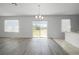 Open living room with gray wood floors, sliding glass doors leading to the backyard, and bright white paint at 1246 Maplebrook Dr, Lake Alfred, FL 33850