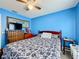 Bright blue bedroom featuring patterned bedding, a wooden dresser, and warm ambiance at 147 Pompei Dr, Kissimmee, FL 34758