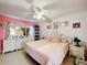 Comfortable bedroom features pink bedding, vintage furniture, a ceiling fan, and bright walls at 147 Pompei Dr, Kissimmee, FL 34758