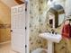 Half-bathroom featuring a pedestal sink and distinctive palm-themed wallpaper at 2340 Palm Tree Dr, Kissimmee, FL 34759