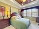 Relaxing main bedroom featuring a tray ceiling, a four-poster bed, and large windows for natural light at 2340 Palm Tree Dr, Kissimmee, FL 34759