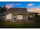 Charming one-story home with a covered porch, lush lawn, and beautiful landscaping at dusk at 2566 Conway Gardens Rd, Orlando, FL 32806