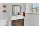 Well-lit powder room featuring a modern vanity with dark wood cabinets and a decorative mirror at 2619 Corvette Ln, Kissimmee, FL 34746