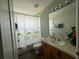 Cozy bathroom featuring a vanity with oak-stained cabinets, a white sink, and a shower with a floral patterned curtain at 2677 Emerald Island Blvd, Kissimmee, FL 34747