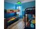 Vibrant blue-walled bedroom featuring bunk beds with superhero-themed bedding and a quirky light fixture at 2677 Emerald Island Blvd, Kissimmee, FL 34747