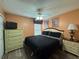 Cozy bedroom featuring dark bedding, dresser, and a ceiling fan, illuminated by bedside lamps at 2677 Emerald Island Blvd, Kissimmee, FL 34747