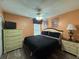 Cozy bedroom featuring dark bedding, dresser, and a ceiling fan, illuminated by bedside lamps at 2677 Emerald Island Blvd, Kissimmee, FL 34747
