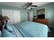 Well-lit bedroom with a ceiling fan, closet, light blue walls, and a wood dresser with TV at 2677 Emerald Island Blvd, Kissimmee, FL 34747
