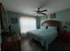 Comfortable bedroom with hardwood floors, a ceiling fan and floral paintings hanging above the bed at 2677 Emerald Island Blvd, Kissimmee, FL 34747