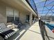 Covered patio area with comfortable lounge furniture and a view of the screened-in pool at 2677 Emerald Island Blvd, Kissimmee, FL 34747