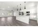 Open-concept kitchen boasts modern pendant lighting, white cabinets, and a large island with countertop seating at 2700 Sw 162Nd St Rd, Ocala, FL 34473