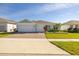 Charming single-story home with a three-car garage, lush landscaping, and a brick-paved driveway at 2719 River Creek Ln, St Cloud, FL 34771