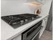Close-up of a gourmet kitchen featuring a cooktop, white backsplash, and quartz countertop at 2719 River Creek Ln, St Cloud, FL 34771