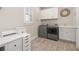 Well-organized laundry room with modern machines, cabinetry and wood-look flooring at 2719 River Creek Ln, St Cloud, FL 34771