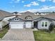 Beautiful, gray single-story home with a three-car garage and brick-paved driveway on a sunny day at 2768 Matera Dr, St Cloud, FL 34771