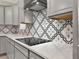 Updated kitchen with grey cabinets, stainless steel appliances, cooktop, modern hood and designer backsplash at 2768 Matera Dr, St Cloud, FL 34771