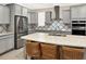Bright eat-in kitchen boasts stainless steel appliances, grey cabinets, patterned backsplash, and an island with seating at 2768 Matera Dr, St Cloud, FL 34771