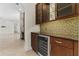 Wet bar with glass-front cabinets, wine cooler, and stylish tile backsplash for entertaining at 304 Acadia Ln, Celebration, FL 34747