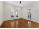 Light-filled bedroom with hardwood floors, three arched windows with plantation shutters, and a ceiling fan at 304 Acadia Ln, Celebration, FL 34747