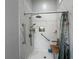 Walk-in shower featuring marble-patterned walls, built-in shelves, and stainless steel grab bars for accessibility and safety at 3874 Blackberry Cir, St Cloud, FL 34769