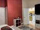 Comfortable bedroom with wood flooring, a pop of red on the accent wall, and a view into the kitchen at 3874 Blackberry Cir, St Cloud, FL 34769