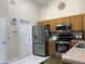 Bright kitchen featuring stainless steel appliances, light wood cabinets, and a white tiled floor at 3874 Blackberry Cir, St Cloud, FL 34769