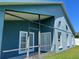 View of the screened in patio of this blue home with well maintained lawn and two sets of doors at 3874 Blackberry Cir, St Cloud, FL 34769