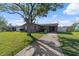 Single-story gray house with a well-manicured lawn and a mature tree providing shade on a sunny day at 4548 Cepeda St, Orlando, FL 32811