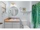 Well-lit bathroom with a round mirror, white sink, and a shower with a tropical-themed curtain at 4743 Vero Beach Pl, Kissimmee, FL 34746