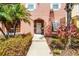 Townhouse exterior with arched entryway and vibrant landscaping in front yard at 4743 Vero Beach Pl, Kissimmee, FL 34746