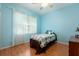 Blue bedroom featuring wood floors, a window, and a bed with a colorful comforter at 4911 Lazy Oaks Way, St Cloud, FL 34771