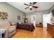 Comfortable bedroom with wood floors, fan, lounge chair, art, and natural light at 4911 Lazy Oaks Way, St Cloud, FL 34771