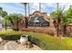 Decorative brick sign for East Lake Cove with lush landscaping and palm trees at 4911 Lazy Oaks Way, St Cloud, FL 34771
