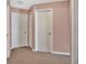 Interior shot of hallway with tan carpet and trim and three white doors at 50 Sawfish Ct, Kissimmee, FL 34759