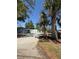 View of gated commercial building featuring a gravel driveway, palm trees, and a secure perimeter fence at 50989 Highway 27 # 210, Davenport, FL 33897