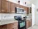 Well-lit kitchen featuring granite countertops, wood cabinets, stainless steel appliances, and tile flooring at 529 Eagle Pointe N, Kissimmee, FL 34746