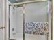 Bathroom shower stall with glass sliding doors, white tiled walls, and floral towel at 6056 Hillside Heights Dr, Lakeland, FL 33812