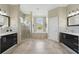 Spacious bathroom featuring tiled floors, a walk-in shower, a soaking tub, and and sinks with dark cabinets at 6132 Waterfield Way, St Cloud, FL 34771